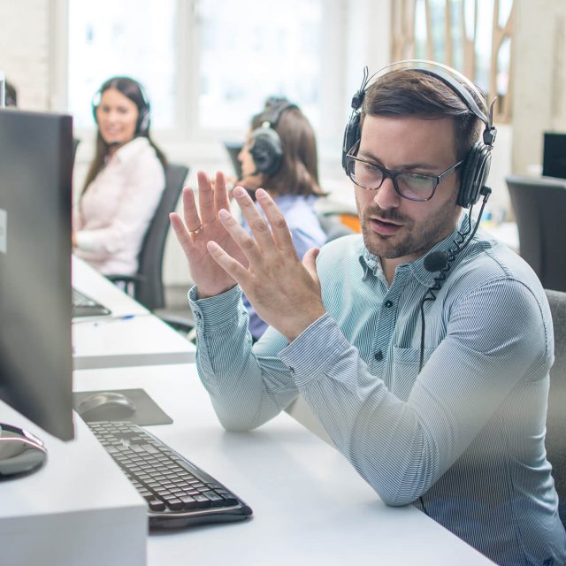 Man on headphones in business setting talking on phone.