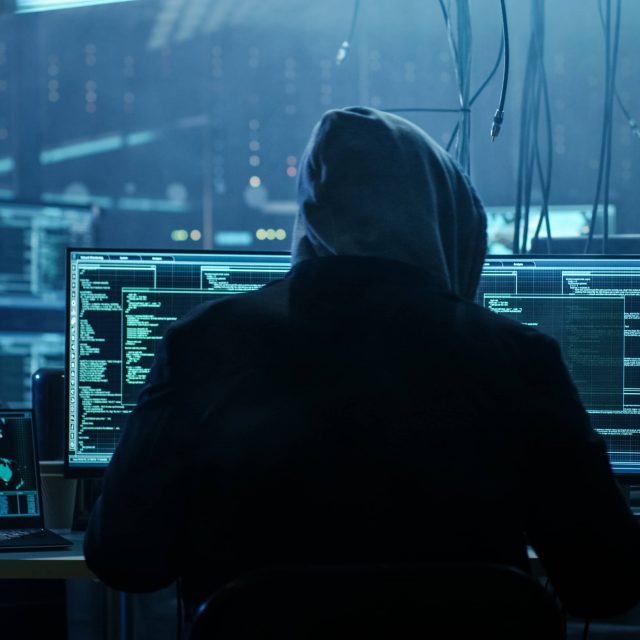 hacker looking at computer monitors.